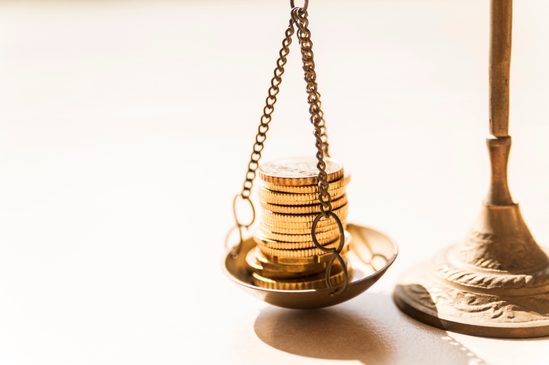 Antique brass scale holding a stack of gold coins